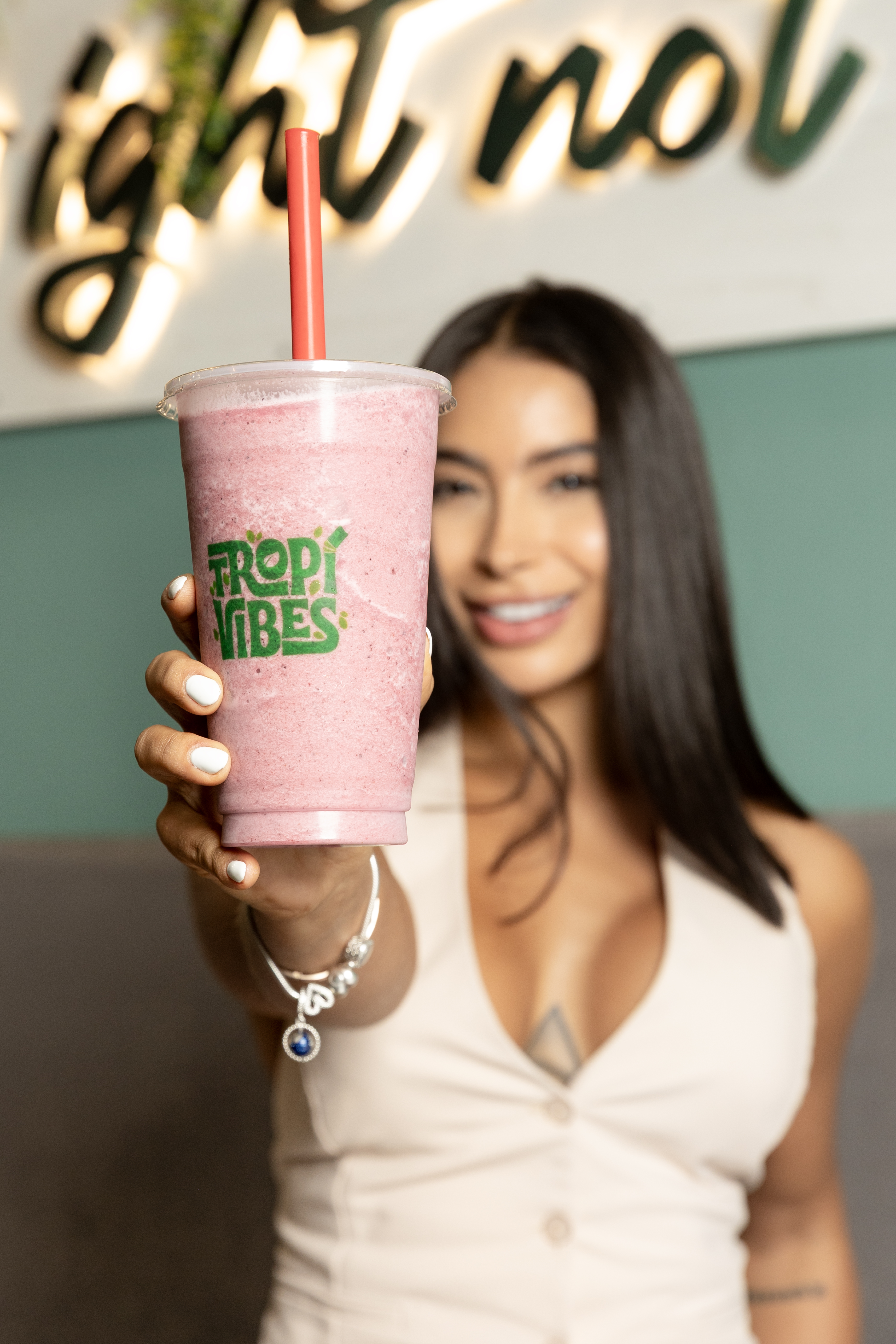 Mujer sonriente sosteniendo smoothie rosa de TROPICO
